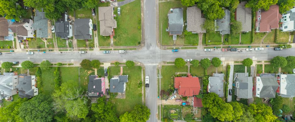 Vizinhança Solidária — Aerial photo capturing an intersection in a suburban neighborhood with houses and greenery.