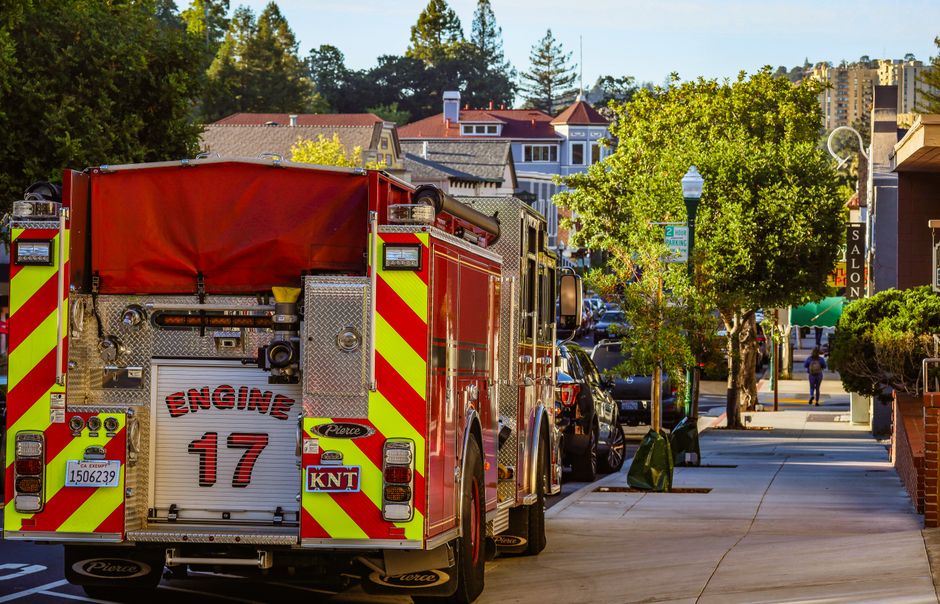Vizinhança Solidária — A fire engine parked on a city street with buildings and clear sky in the background.
